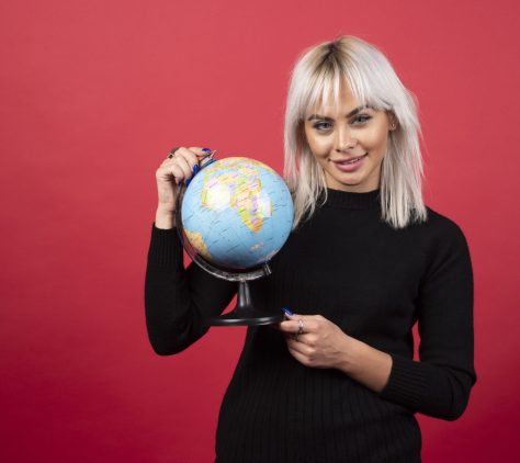 Portrait of woman holding an Earth globe on a red background. High quality photo